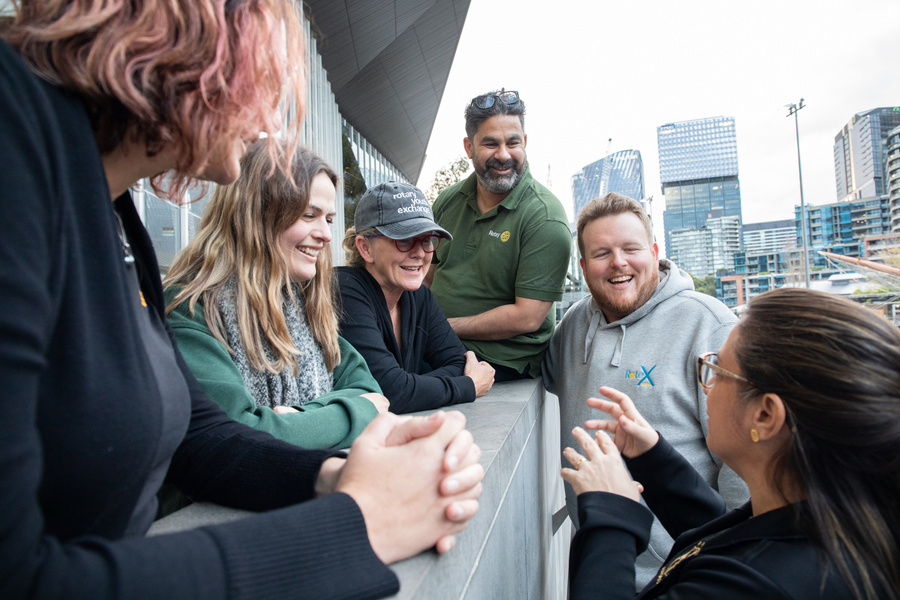 a group of rotary members sitting on a bench talking to each other