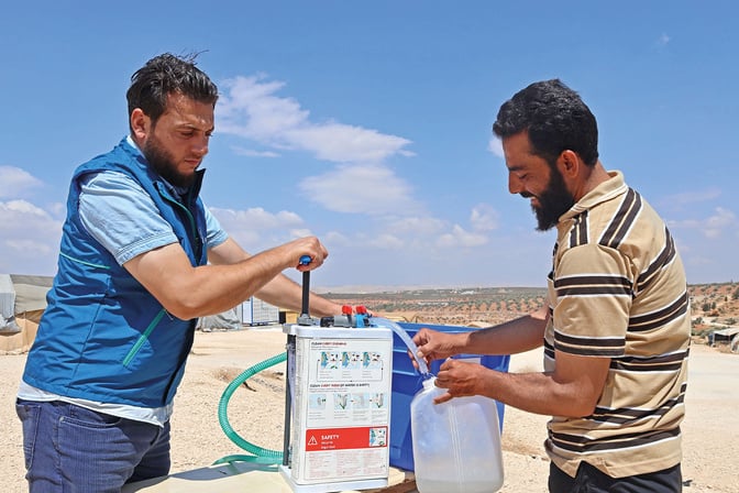 two people are filling up water from a container