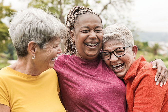 three people laughing together in the park