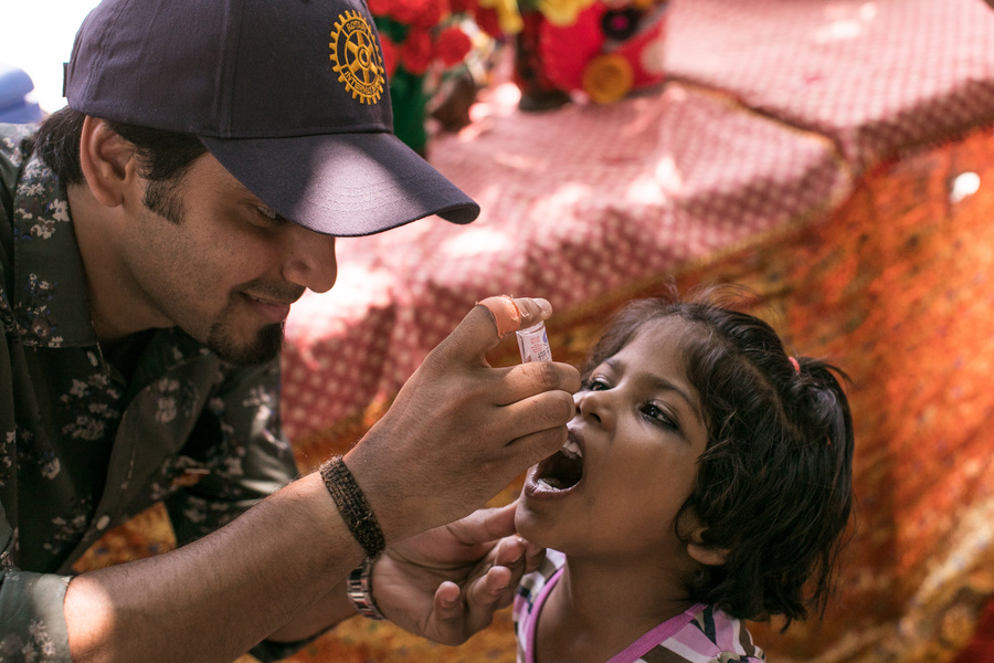 A man gives a child an oral polio vaccine