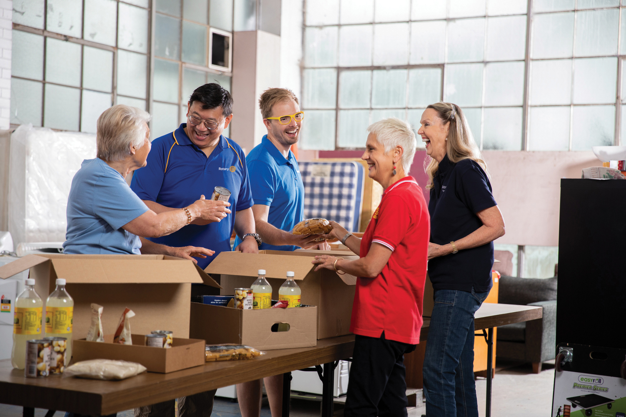 a group of people standing around a table with boxes of food